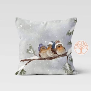 Three birds wearing purple and blue hats are perched on a snowy branch. The birds are brown and white with black eyes. The background is a light blue watercolor wash with white snowflakes.