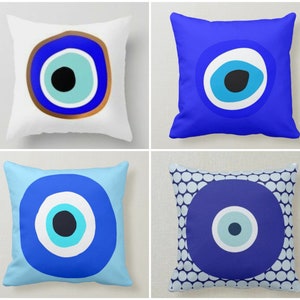 May include: Four different pillow designs featuring the evil eye symbol. The evil eye is a blue circle with a white center and a black pupil. The pillows are all square and have a white background.