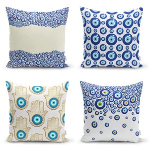 May include: Four decorative pillow covers with different patterns featuring the evil eye symbol. The patterns include a white background with blue evil eyes, a white background with blue evil eyes and gold hamsa hands, a white background with blue evil eyes in a wave pattern, and a white background with blue evil eyes in a scattered pattern.
