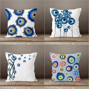 May include: Four decorative throw pillows with different patterns featuring the evil eye symbol in blue and white. The pillows are on a light brown surface.