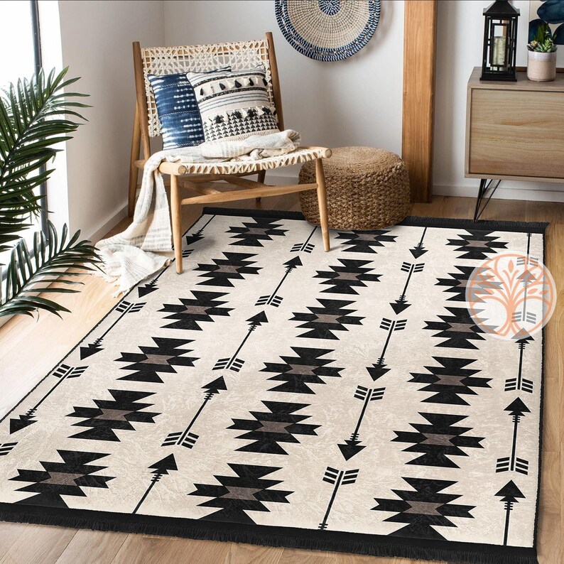 May include: A black and white geometric rug with a southwestern design featuring arrows and diamond shapes. The rug has a fringe border.