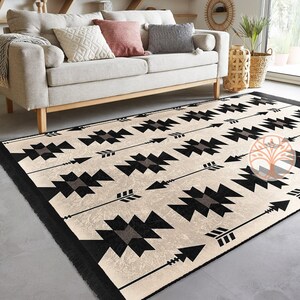 May include: A black and white geometric rug with a cream background. The rug features a repeating pattern of arrows and geometric shapes.