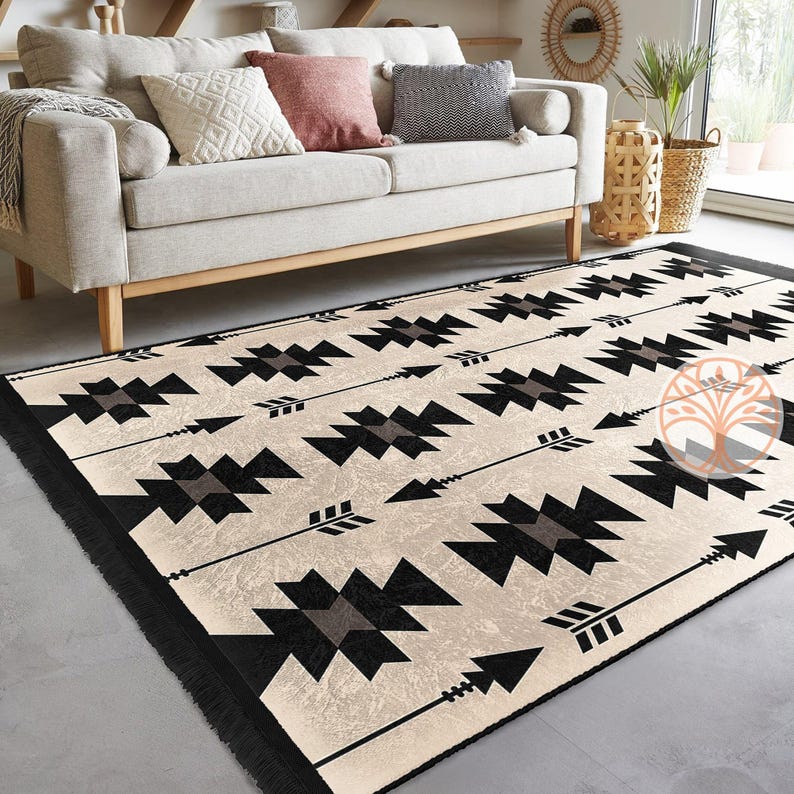 May include: A black and white geometric rug with a cream background. The rug features a repeating pattern of arrows and geometric shapes.