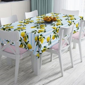 May include: A blue and white striped tablecloth with a lemon pattern. The tablecloth is on a table with four white chairs.