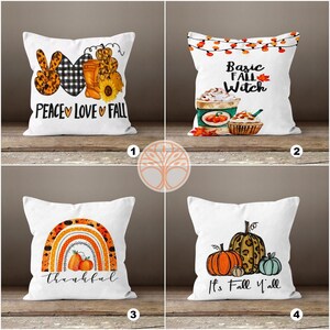 May include: Four different throw pillow designs with fall themes. The first pillow has a peace sign, a heart, and the words "Peace Love Fall". The second pillow has a coffee cup, a cupcake, and the words "Basic Fall Witch". The third pillow has a rainbow with the word "thankful" underneath. The fourth pillow has three pumpkins and the words "It's Fall Y'all".