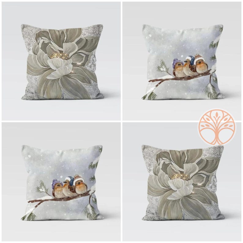 Two birds wearing winter hats are perched on a branch of a snowy tree. The birds are brown and white with blue accents. The background is a soft blue with white snowflakes. The image is a decorative pillow design.
