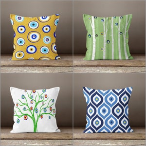 May include: Four decorative throw pillows with different patterns. The first pillow has a yellow background with blue and white evil eye designs. The second pillow has a green background with white birch trees and blue evil eyes. The third pillow has a white background with a green tree with blue and red evil eyes. The fourth pillow has a blue and white geometric pattern.