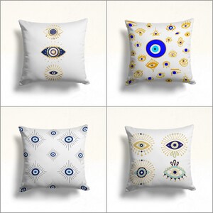 May include: Four white pillow covers with different patterns of blue and gold evil eyes. The evil eyes are a symbol of protection against bad luck.