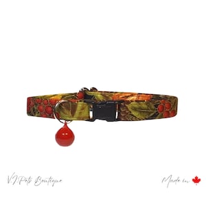 May include: A green, red, and brown cat collar with a red bell. The collar has a floral pattern with leaves and berries. The collar is made in Canada.