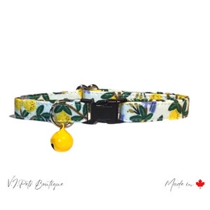 May include: A white cat collar with a yellow lemon print and a yellow bell. The collar has a black buckle and is made in Canada. V.J. Pets Boutique.