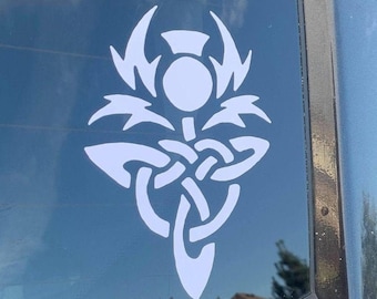 May include: A white vinyl sticker of a stylized thistle with a Celtic knot design on a black car window.