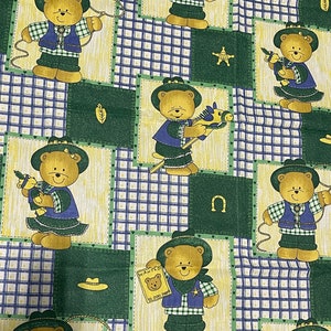 May include: A green, blue, and yellow fabric with a repeating pattern of teddy bears wearing cowboy hats and vests. The bears are holding a lasso, a toy horse, and a toy gun. The fabric also features a sheriff's star, a horseshoe, and the words "WANTED" and "10,000 dead".