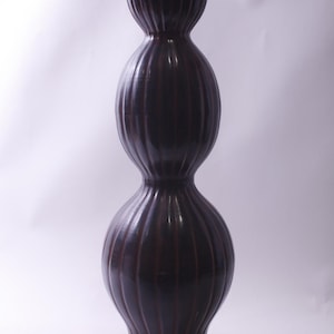 Puede incluir: Un jarrón alto de cerámica marrón oscuro con un diseño apilado único. El jarrón tiene una textura acanalada y un acabado brillante. El jarrón mide aproximadamente 76 cm de alto, con una forma bulbosa en la base, el centro y la parte superior.