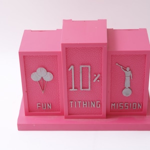 May include: Pink three-sectioned money box with slots labeled "Fun", "Tithing 10%", and "Mission". Each section has a silver design: balloons, a number "10%", and a figure with a trumpet.