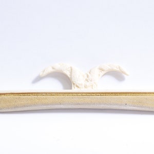 Peut inclure: Un cintre en plastique blanc avec un dessus décoratif et un fond rembourré. Le cintre est conçu pour tenir les vêtements sans laisser de plis.