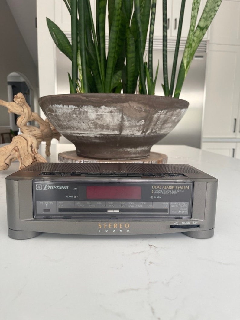 Pu&ograve; includere: Un radio sveglia stereo Emerson grigio con un sistema di doppia sveglia e un display digitale rosso. La radio ha un sintonizzatore digitale con bande AM e FM e un lettore di cassette. Il radio sveglia ha un sistema di doppia sveglia con un pulsante snooze.