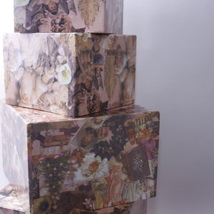 Puede incluir: Una pila de cuatro cajas cuadradas, cada una con un collage de imágenes vintage. Las cajas están apiladas en forma de pirámide, con la caja más grande en la base y la más pequeña en la cima. Las imágenes en las cajas son principalmente en tonos marrones, blancos y negros.