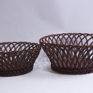 Könnte beinhalten: Zwei braune geflochtene Körbe, einer größer als der andere, mit einem dekorativen, offenen Flechtmuster.