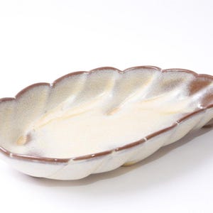 Pode incluir: Um conjunto de três canecas de cerâmica com acabamento salpicado e fosco. As canecas são em tons de creme, cinza claro e cinza escuro. Cada caneca tem um design simples e minimalista e uma alça arredondada. As canecas estão empilhadas.