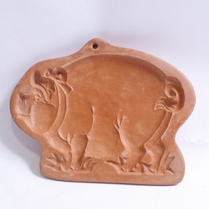 Może przedstawiać: Forma do ciasteczek z terakoty w kształcie świni. Świnia stoi na czterech łapach i ma szczegółowy wzór.