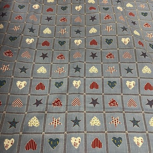 May include: Blue fabric with a repeating pattern of red, white, and blue hearts and stars. The fabric has a checkered pattern.