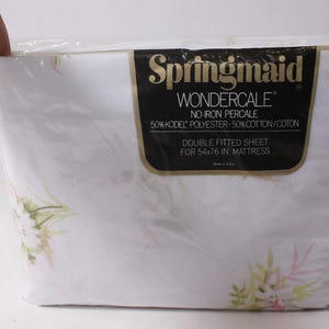 Puede incluir: Una sábana bajera doble Springmaid Wondercale en embalaje de plástico para un colchón de 137x193 cm. La sábana presenta un estampado floral con hojas rosas y verdes. La etiqueta especifica 50% poliéster Kodel y 50% algodón percal.