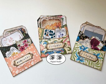 May include: Three decorative paper envelopes with floral patterns and vintage-style designs. Each envelope has a label with the words "Memories", "Journey", and "Journal".