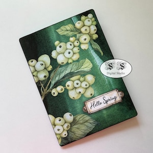 Puede incluir: Una tarjeta de acuarela verde con bayas blancas y hojas. La tarjeta tiene una etiqueta de metal con el texto "Hello Spring" en ella.