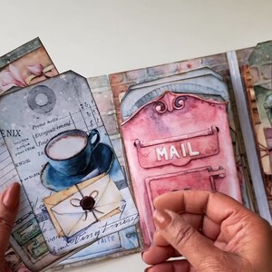 May include: A scrapbook with a vintage mail theme. The pages feature images of mailboxes, letters, and a cup of coffee. The scrapbook is decorated with paper scraps, tags, and embellishments.