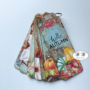 May include: A set of colorful fall-themed bookmarks with a variety of autumnal designs, including pumpkins, gourds, and leaves. The bookmarks are decorated with a rustic, vintage aesthetic and feature the text "hello autumn".