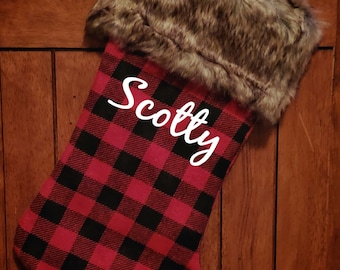 May include: Red and black plaid Christmas stocking with a faux fur cuff and the name "Scotty" embroidered on the front.