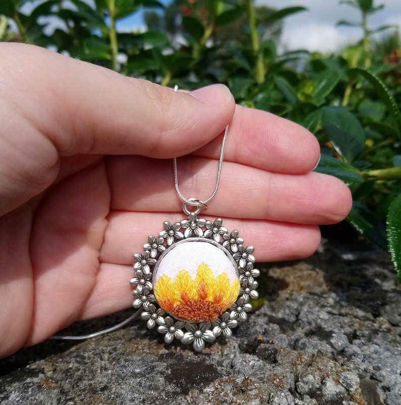 Sunflower embroidered onto a silver floral pendant