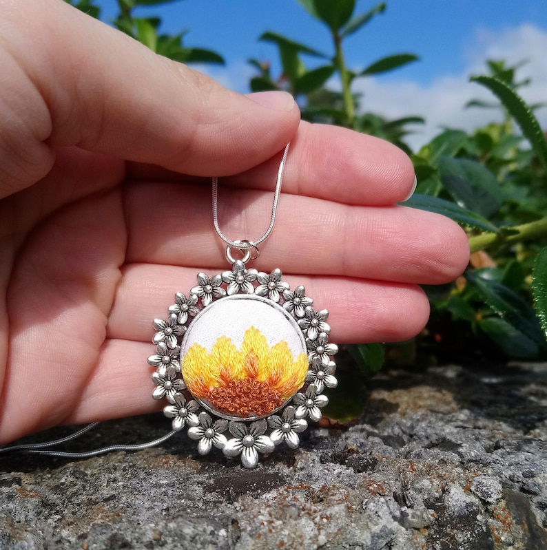Sunflower embroidered onto a silver floral pendant