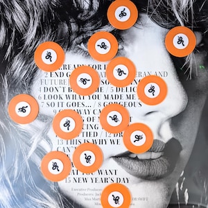 May include: A black and white image of a woman's face with orange circular stickers featuring a white snake design. The stickers are scattered across the image. The background includes song lyrics.