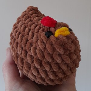 Puede incluir: Un juguete de peluche marr&oacute;n con forma de pollo con detalles rojos y amarillos. El pollo hecho a mano tiene ojos negros y un exterior suave y texturizado. El juguete est&aacute; dise&ntilde;ado para parecerse a un pollo.