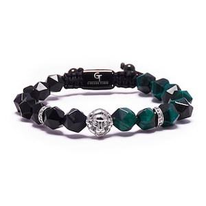 May include: Black and green beaded bracelet with a silver lion head charm. The bracelet has a black cord with the text "GT COLLECTION" on a silver tag.