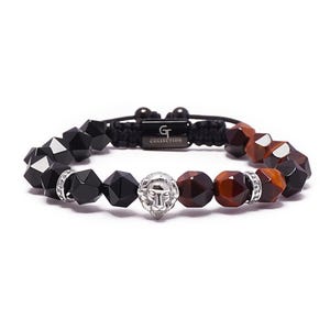 May include: Black and brown beaded bracelet with a silver lion head charm. The bracelet has a black cord with the text "GT COLLECTION" on a silver tag.