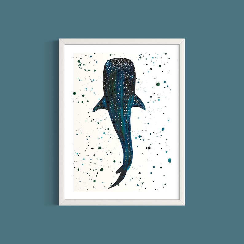 May include: A framed art print featuring a whale shark illustration. The whale shark is depicted in shades of blue and green with white spots, set against a white background with scattered green and black paint splatters. The artwork is framed in a white border.