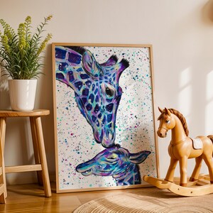 May include: A framed rectangular wall art print featuring a colorful, abstract painting of an adult giraffe nuzzling a baby giraffe. The artwork uses vibrant shades of blue, purple, and pink with paint splatters on a white background.