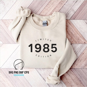 Può includere: Una felpa beige con testo nero che recita "LIMITED 1985 EDITION".