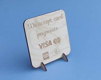 Op de afbeelding: Een houten bord met de tekst "We accept card payments VISA Mastercard American Express" en een contactloos betalingssymbool.