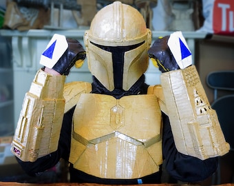 May include: A person wearing a gold-colored, cardboard-like costume with a helmet. The costume has a detailed design and appears to be a homemade creation.