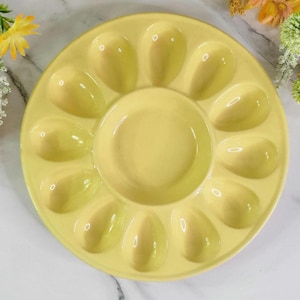 May include: A yellow ceramic egg plate with 10 individual indentations for serving deviled eggs or other appetizers.