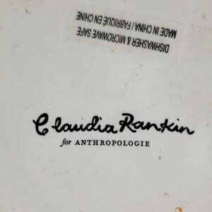 May include: A white ceramic dish with black text that reads "Claudia Rankin for Anthropologie". The dish is microwave and dishwasher safe and made in China.
