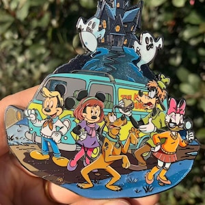 Könnte beinhalten: Ein farbenfroher Emaille-Pin mit einem Spukhaus, Geistern und einem Van mit Zeichentrickfiguren. Zu den Figuren gehören Micky Maus, Minnie Maus, Goofy, Pluto und Daisy Duck. Der Van trägt den Text "The K Mag".