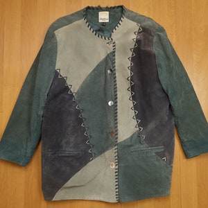 Puede incluir: Una chaqueta de ante verde, azul y gris con cierre de botones y costuras decorativas. La chaqueta tiene un diseño de patchwork con paneles de diferentes colores.