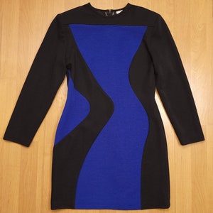 May include: A long-sleeved dress with a blue and black color block design. The dress has a fitted silhouette and a round neckline.