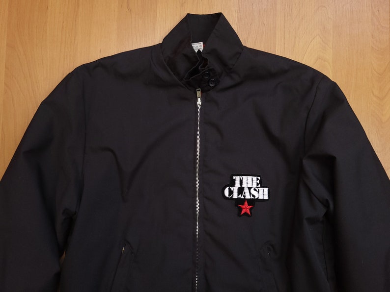 Peut inclure: Une veste bomber noire avec une fermeture &eacute;clair et un patch blanc "The Clash" avec une &eacute;toile rouge.