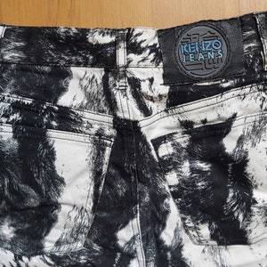 May include: The rear view of high-waisted jeans with a striking black and white pattern. The jeans feature two back pockets and a leather patch with the "KENZO JEANS" logo. The pattern is abstract.