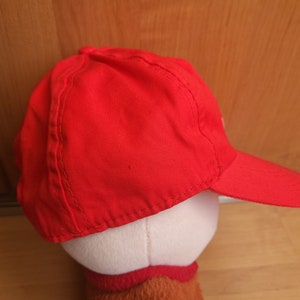 May include: A red baseball cap with a curved brim. The cap is made of a soft, cotton fabric.